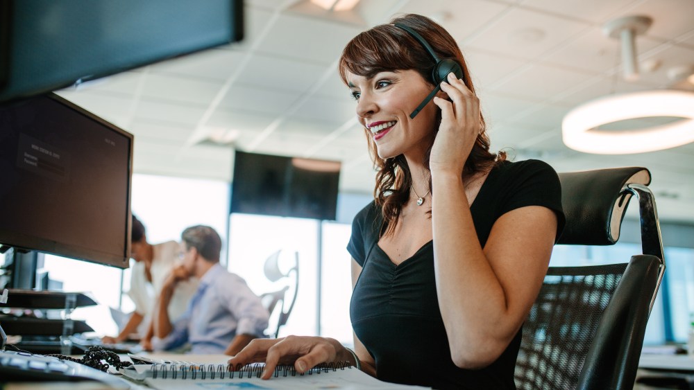 Call center business woman talking on headset. Caucasian female in customer service position talking on the phone.