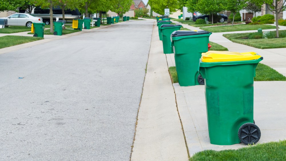 Row of garbage bins lined up along the roadside in a neat urban suburb waiting to be collected for disposal of the rubbish