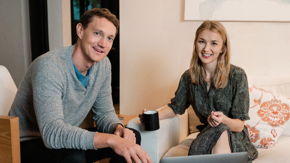 A seated photo of smiling Archive cofounders Ryan Rowe and Emily Gittins in a neutral living room setting.