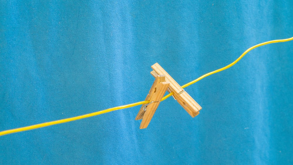 PRODUCTION - 03 September 2022, Brandenburg, Kyritz: Two wooden clothespins hang on a yellow clothesline outside, behind them hangs a blue towel. Photo by: Viola Lopes/picture-alliance/dpa/AP Images