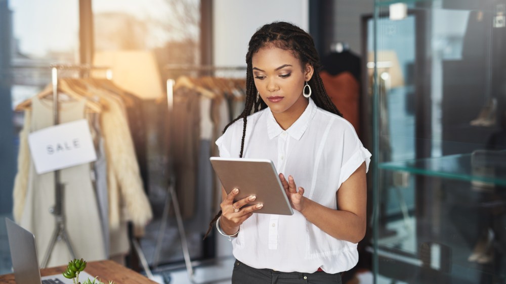 Cropped shot of a young business owner using her tablet while standing in her store