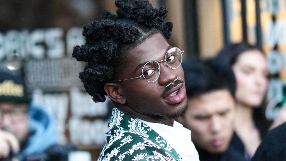 NEW YORK, NEW YORK - FEBRUARY 14: Lil Nas X wears circle glasses, a silver large nose piercing, a white shirt, a green with white print pattern blazer jacket , outside Thom Browne, during New York Fashion Week, on February 14, 2023 in New York City. (Photo by Edward Berthelot/Getty Images)