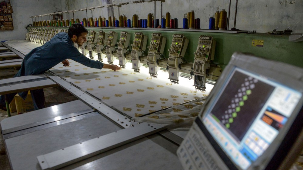 A worker operates an embroidery panel machine to design on fabric at a small factory in Peshawar on September 10, 2020.
