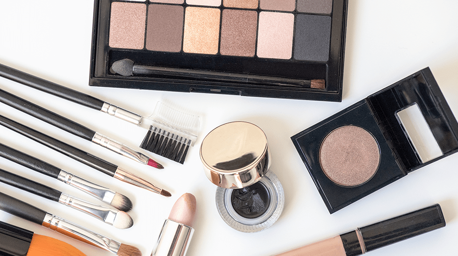 Makeup products and makeup brushes on a clean white surface