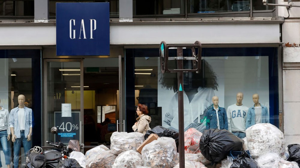 PARIS, FRANCE - MARCH 23: A pedestrian walks past garbage bags piled up in front of a Gap store during the refuse collectors' strike, the day of nationwide mass protests after France's pension reform passed parliament on March 23, 2023 in Paris, France. The strike of Parisian garbage collectors' continues after the French Government pushed its pension reform through parliament without a vote after enacting article 49.3 of the constitution. Labour unions had fought the government's pension reform with months of protests in a bid to stop the government increasing the retirement age in France from 62 to 64. (Photo by Chesnot/Getty Images)
