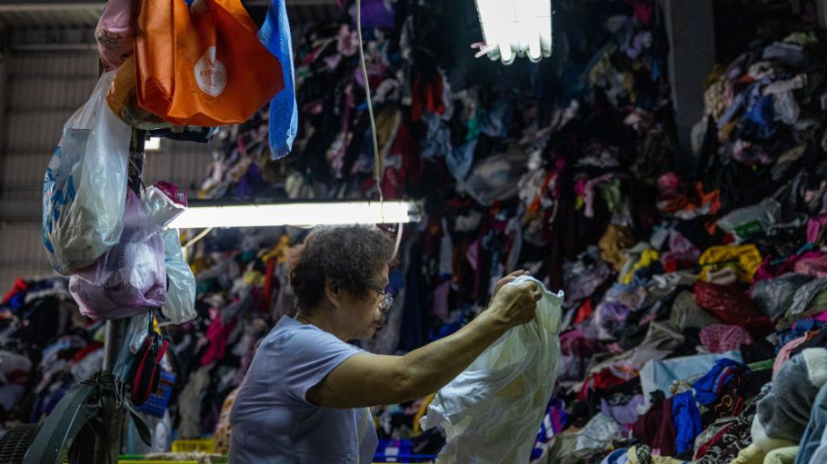 An employee sorts through a pile of second-hand clothes at a facility operated by Zheng-chuan textile recycling factory on July 15, 2022 in New Taipei City, Taiwan.