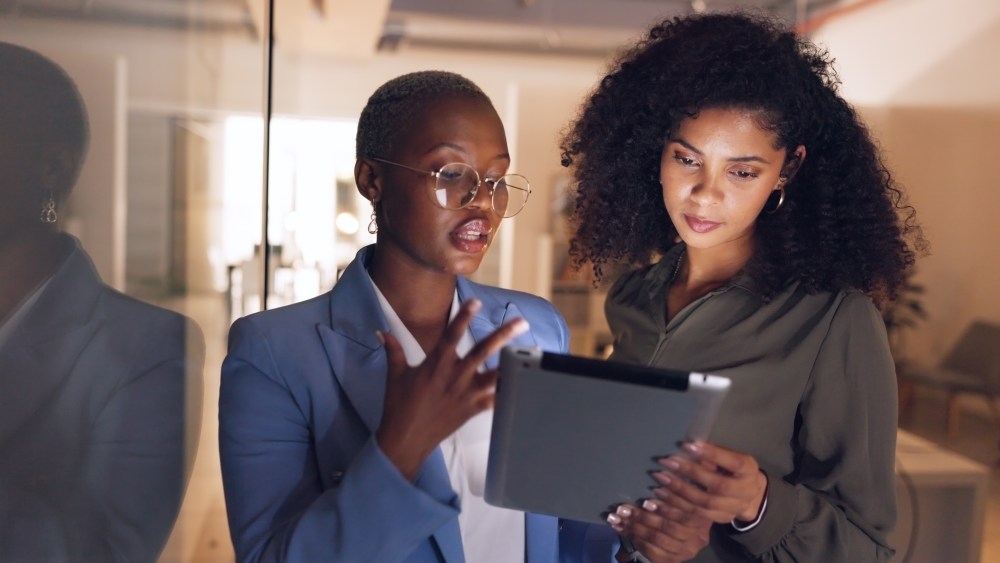 Black women, business and tablet in discussion or meeting for corporate strategy, planning or collaboration at office. African woman executive talking to employee on touch screen technology at work.