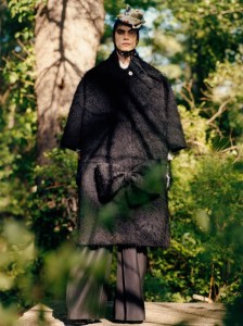 Maison Margiela’s black tactile viscose Neoprene-bonded coat with a bow detail, Ernest Baker’s cotton shirt and Dior wool pants. Rick Owens boots; Maison Margiela Recicla Mickey Mouse cadet hat with a black tulle fascinator.