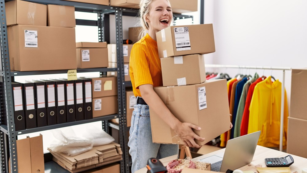 Young blonde woman working at small business ecommerce celebrating crazy and amazed for success with open eyes screaming excited.