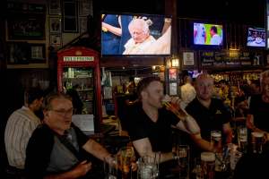 People watch coverage of the coronation of Britain's King Charles III at a pub in Bangkok on May 6, 2023. (Photo by Jack TAYLOR / AFP) (Photo by JACK TAYLOR/AFP via Getty Images)