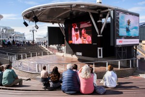 People watch live broadcast of coronation of the Britain's King Charles III on a big screen at the Waterfront touristic venue, in Cape Town, on May 6, 2023. (Photo by RODGER BOSCH / AFP) (Photo by RODGER BOSCH/AFP via Getty Images)