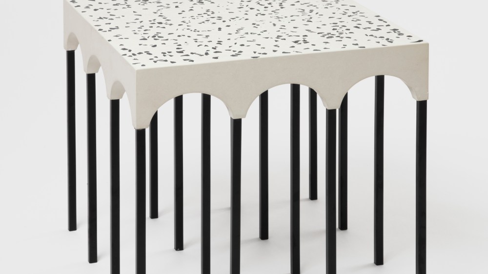 Work by Germane Barnes shows what appears to be a table top white and speckled black with 16 slider black legs.