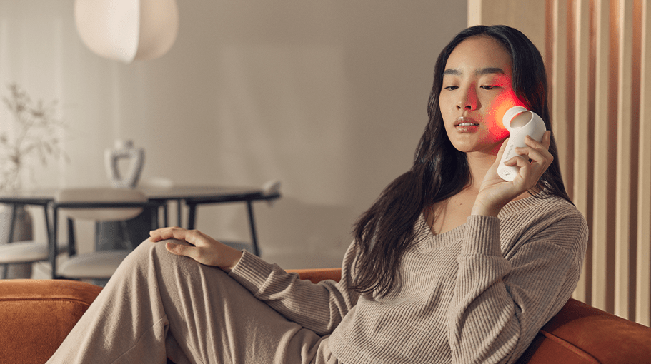 woman at home using a facial tool with red light therapy