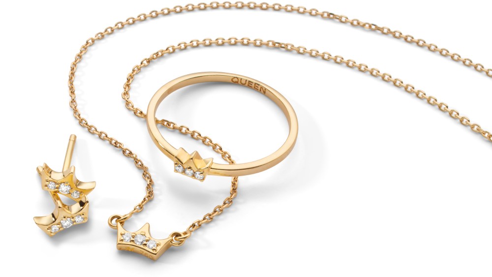 Jewelry from the Queen Tiara collection; a pair of gold stud earrings shaped like a tiara with three diamonds, a delicate gold necklace with a tiny tiara with three diamonds and a gold ring with a tiny tiara with three diamonds. Shown on a white background.