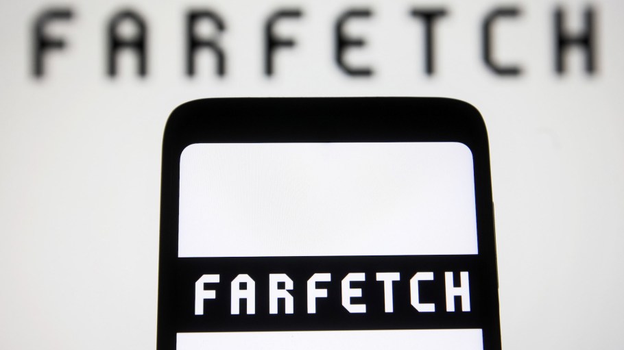 In this photo illustration, the Farfetch logo is displayed on a smartphone screen and in the background.