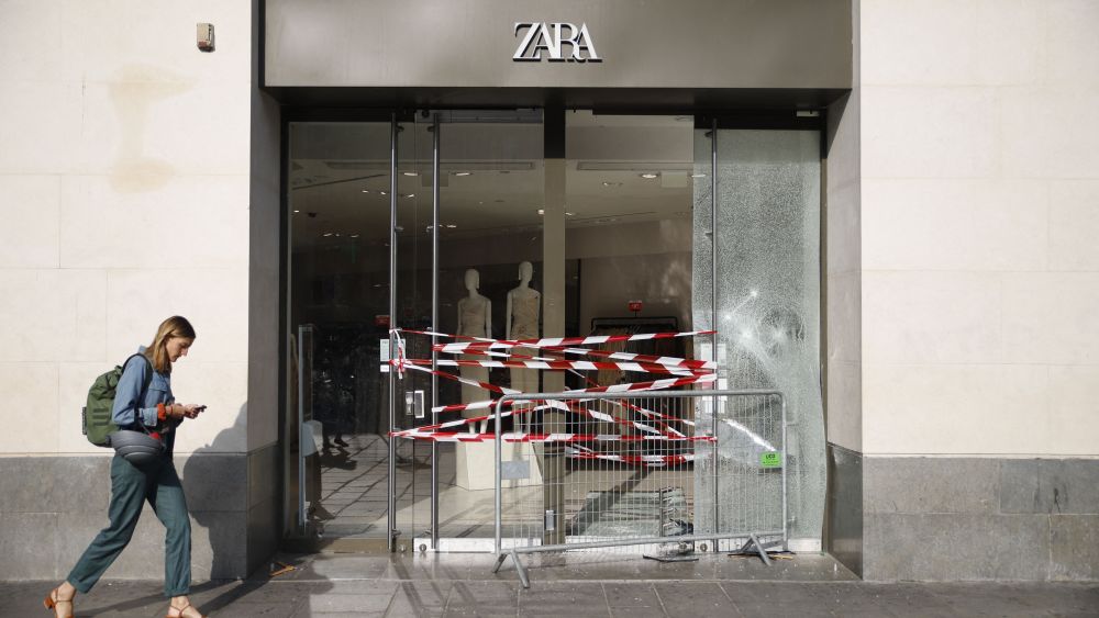 A pedestrian walks past the entrance to a damaged store in Paris on June 30, 2023, after protests following the shooting of a teenage driver by French police in the Paris suburb of Nanterre on June 27. French President Emmanuel Macron was scheduled to chair a new crisis meeting of ministers after a third straight night of nationwide protests over the deadly police shooting of a teenager saw cars torched, shops ransacked and hundreds arrested. (Photo by AFP) (Photo by -/AFP via Getty Images)