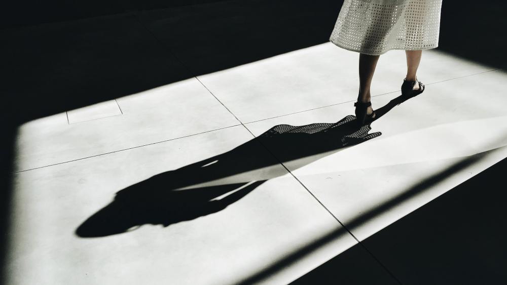 An image from Apparel Impact Institute's 2023 roadmap progress report showing a woman in heels striding across a shadowed floor.