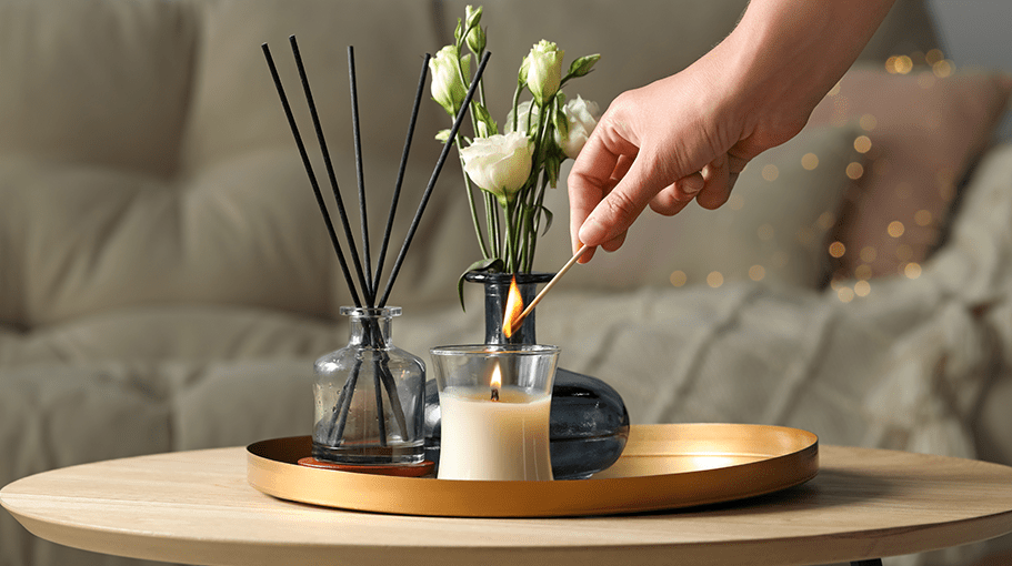 Woman lighting candle at wooden table in living room, closeup