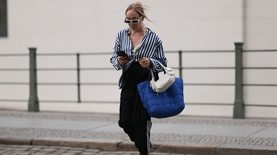 BERLIN, GERMANY - SEPTEMBER 03: Sonia Lyson seen wearing Linda Farrow white sunglasses, Zara blue / white striped blouse, Adidas black jogger cargo pants, Miu Miu black / white knit crochet bra, Miu Miu Wandler white pocket bag, brown tortoise hair clip, Vee Collective royal blue nylon stepped shopper bag and Copenhagen Studios black suede leather boots, on September 03, 2023 in Berlin, Germany. (Photo by Jeremy Moeller/Getty Images)