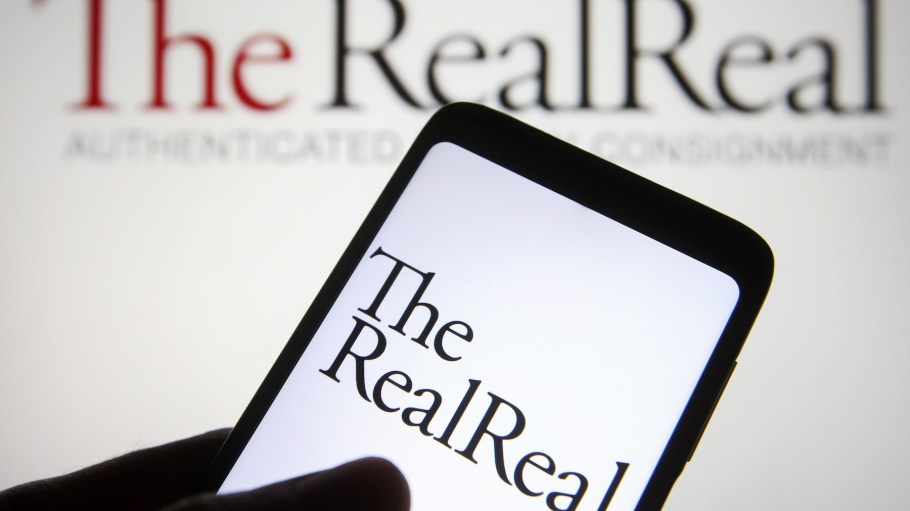 The RealReal Inc. logo is seen on a smartphone screen and in the background.