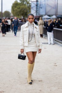 PARIS, FRANCE - OCTOBER 03: Lori Harvey wears white jacket, skirt, turtleneck, necklace, black bag, beige boots outside Chanel during the Womenswear Spring/Summer 2024 as part of  Paris Fashion Week on October 03, 2023 in Paris, France. (Photo by Christian Vierig/Getty Images)