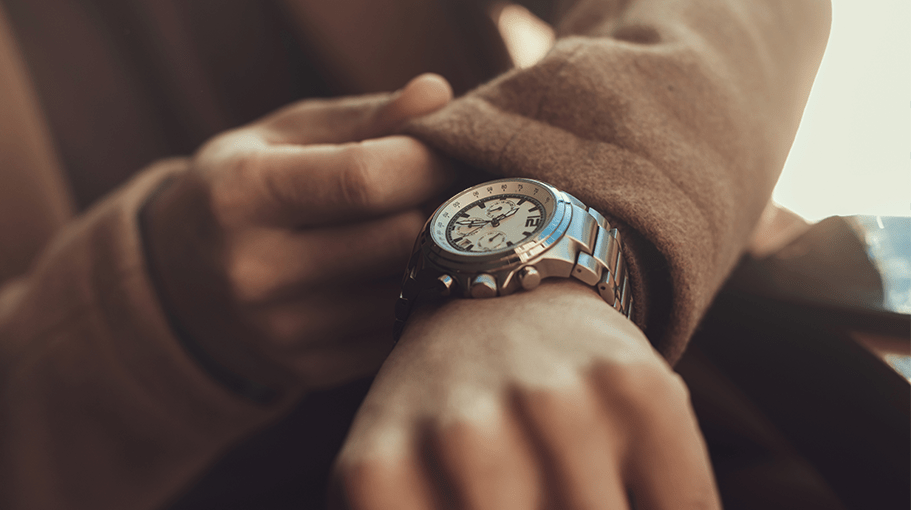 Young man checking time on his elegant wristwatch