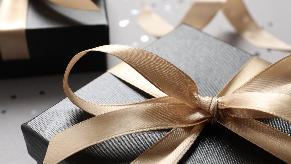 Beautiful gift box with bow on grey background, closeup view