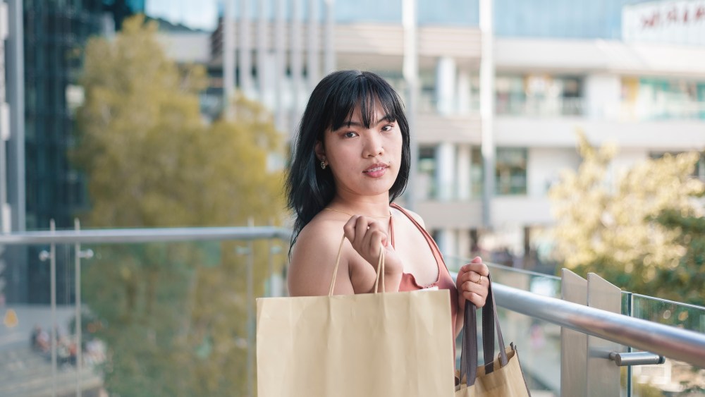 A fashionable young asian woman flaunting her shopping bags. Scene at a luxury shopping mall.