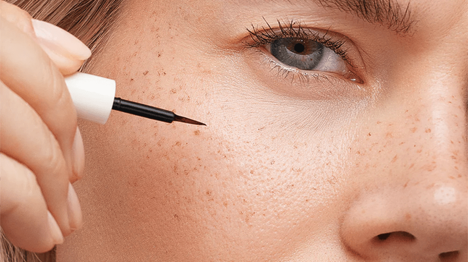 woman applying faux freckles with a freckle pen