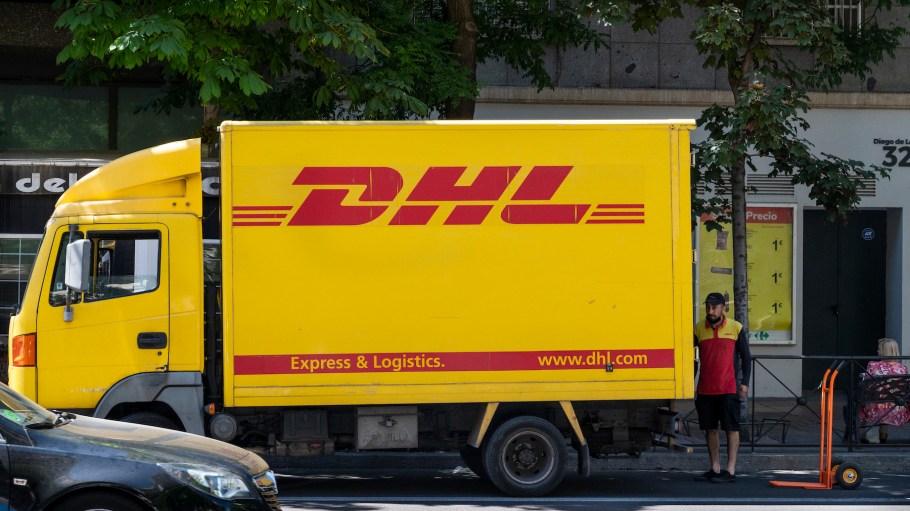 German express delivery mail company DHL courier prepares packages inside the delivery truck parked on the street in Spain.