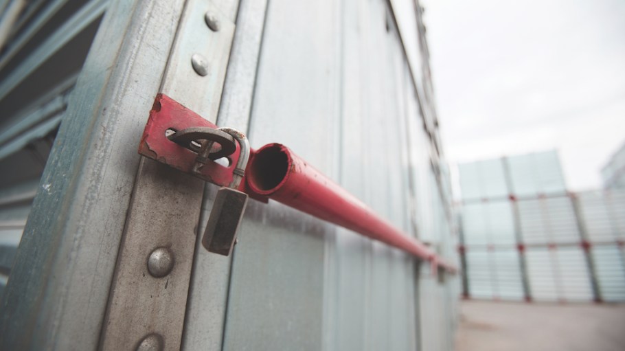 Close-up of sealed metal shipping container, hanging open lock after burglary