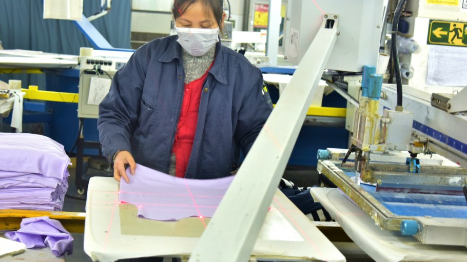 A woman in an apparel factory measuring garments.
