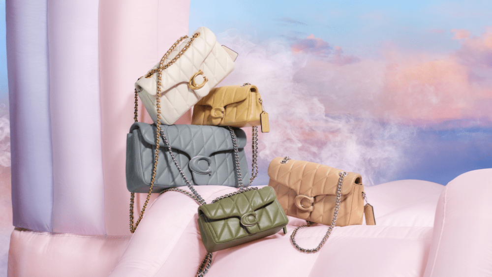 five bags in various pastel tones are shown stacked in front of a purple sunset background
