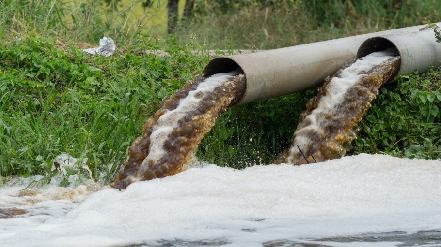 Polluted water runs out of pipes into a river.