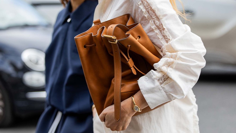 woman carrying brown leather bucket bag