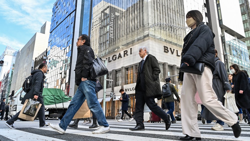 Pedestrians cross the street in front of luxury shops in the Ginza shopping district in Tokyo.
