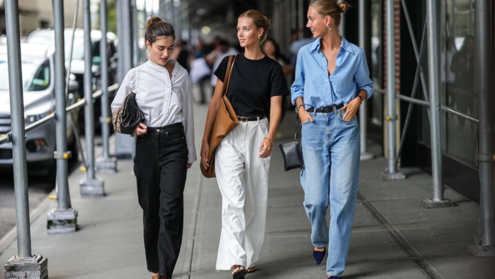 three women walking under city scaffolding wearing summer outfits