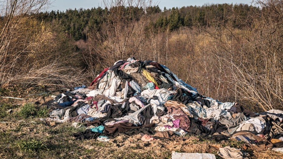 Heap of clothes, illegal dump garbage in the forest. Pollution problem