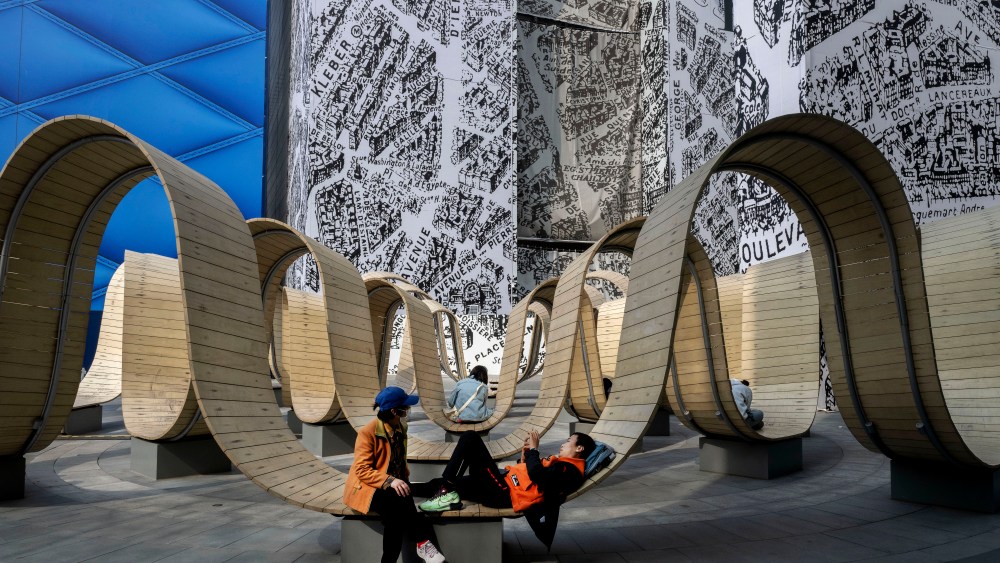 People resting on designer seats surrounded by a Louis Vuitton and a Dior store, soon to be opened at Beijing's Taikoo Li Sanlitun retail district.