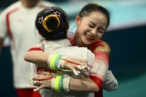 China's Zhang Yihan  hugs China's Qiu Qiyuan after competing in the uneven bars event of the artistic gymnastics women's team final during the Paris 2024 Olympic Games at the Bercy Arena in Paris, on July 30, 2024.
