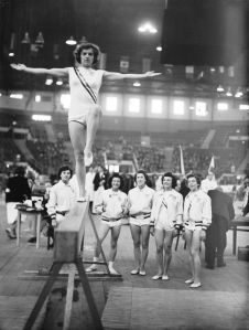 Marian Barone (1924 - 1996) of the USA on the balance beam at Empress Hall, Earl's Court, during the gymnastics events at the London Olympic Games, 12th August 1948. Looking on are other members of the American team. (Photo by Keystone/Hulton Archive/Getty Images)