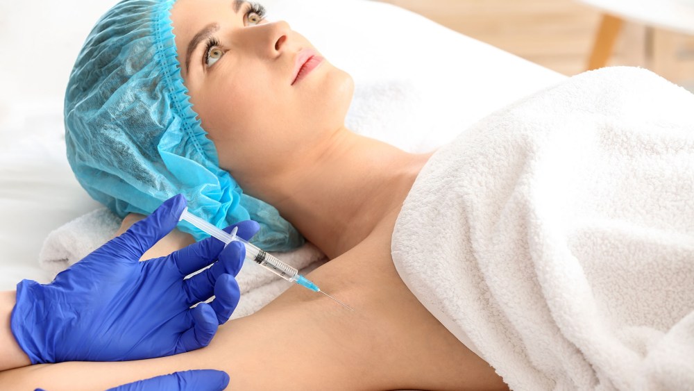Woman receiving botox injection in armpit as treatment of hyperhidrosis in beauty salon