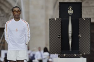 US rapper, artist and designer Pharell Williams stands next to a trunk custom-designed by Louis Vuitton containing the Olympic torch as part of the 2024 Paris Olympic Games Torch Relay, on the day of the opening ceremony, in Saint-Denis, outside Paris, on July 26, 2024. (Photo by STEPHANE DE SAKUTIN / POOL / AFP) (Photo by STEPHANE DE SAKUTIN/POOL/AFP via Getty Images)