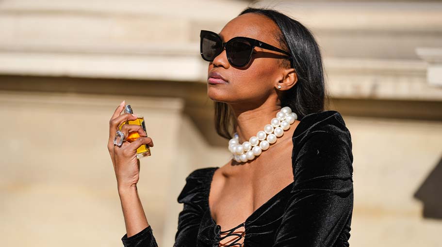 women wearing sunglasses applying perfume