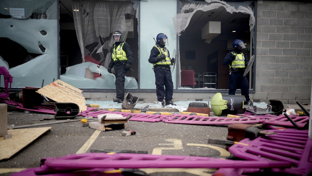 Riot police stand amongst debris and broken windows in Rotherham, England.