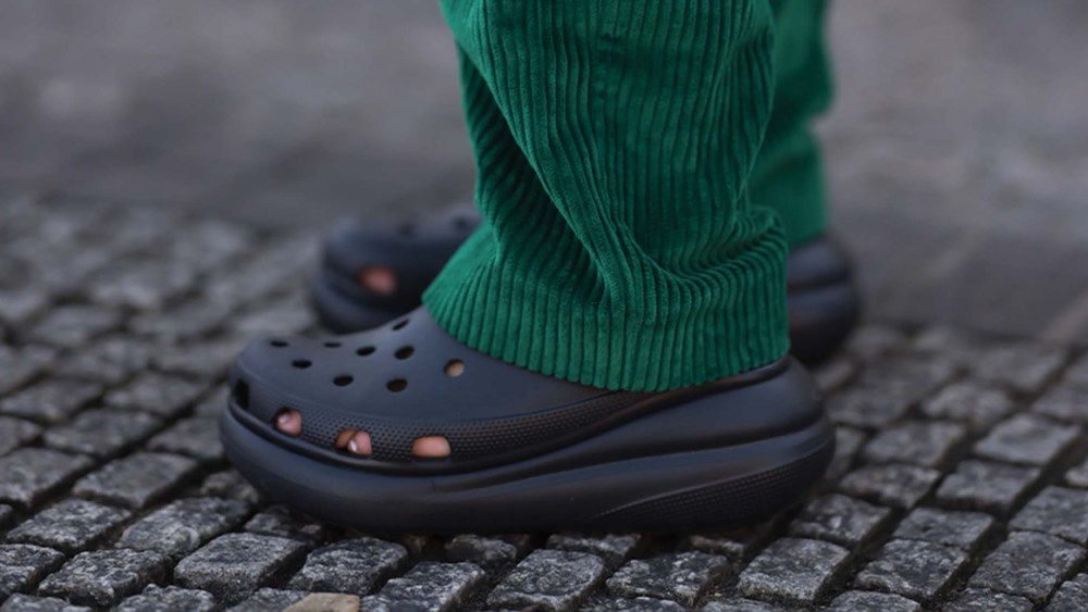 person wearing black Crocs shoes and green pants
