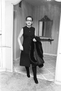 Opera singer Maria Calls with her coat over her arm wearing a button-up shirt-dress with boots and tinted glasses in 1970..Article title: 'Callas on Callas'.