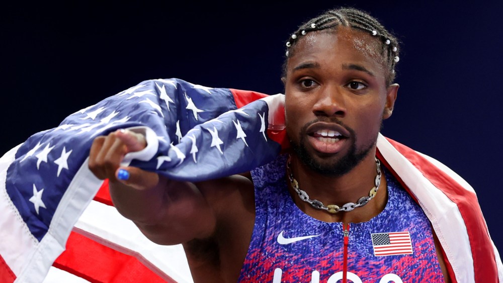PARIS, FRANCE - AUGUST 04: Noah Lyles wearing necklace for photo finish of Team United States celebrates winning the gold medal in the Men's 100m Final on day nine of the Olympic Games Paris 2024 at Stade de France on August 04, 2024 in Paris, France. (Photo by Julian Finney/Getty Images), gold medal