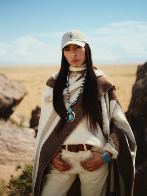 Quannah Chasinghorse wears Polo Ralph Lauren x Naiomi Glasses collection cream and brown wrap with Polo Ralph Lauren cream baseball cap and turquoise jewelry. Navajo Nation land is the backdrop.