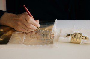 An embroiderer at Lesage works on a quilted gold cross.